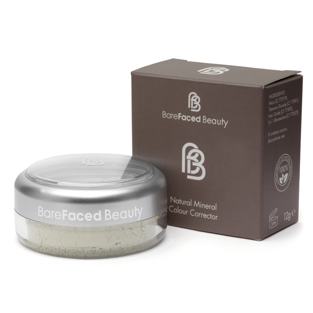 A small round clear pot of natural mineral colour corrector placed in front of a taupe/chocolate brown square box, which is the packaging it comes in.