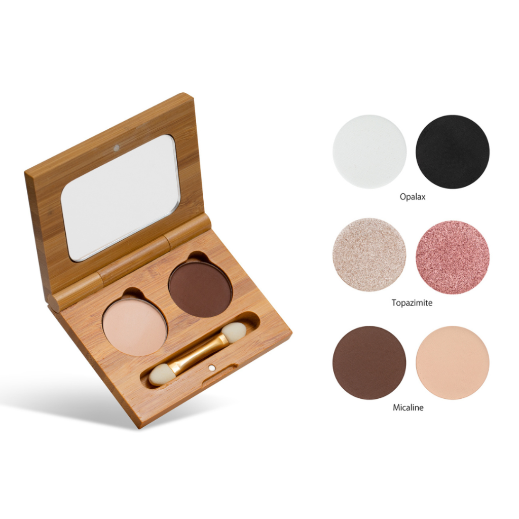 photo of bomonde mineral make up's eyelshadow duo and double ended mini eyeshadow brush on a white background. the eyeshadows are pressed into a round pan and encased in a bamboo compact case with mirror. the eyeshadows are nude and dark brown. To the right, are swatches from top to bottom Opalax (black and white shadows), Topazimite (shimmer nude and pink shadows) and Micaline (nude and dark brown shadows)