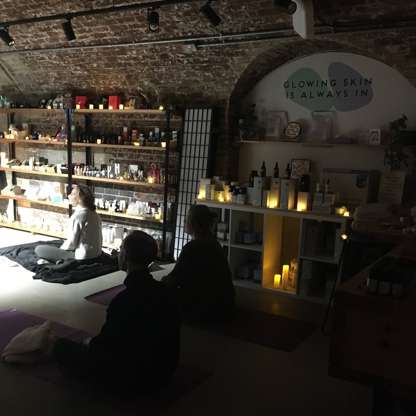 people meditating by candlelight in old railway arch in london coal drops yard