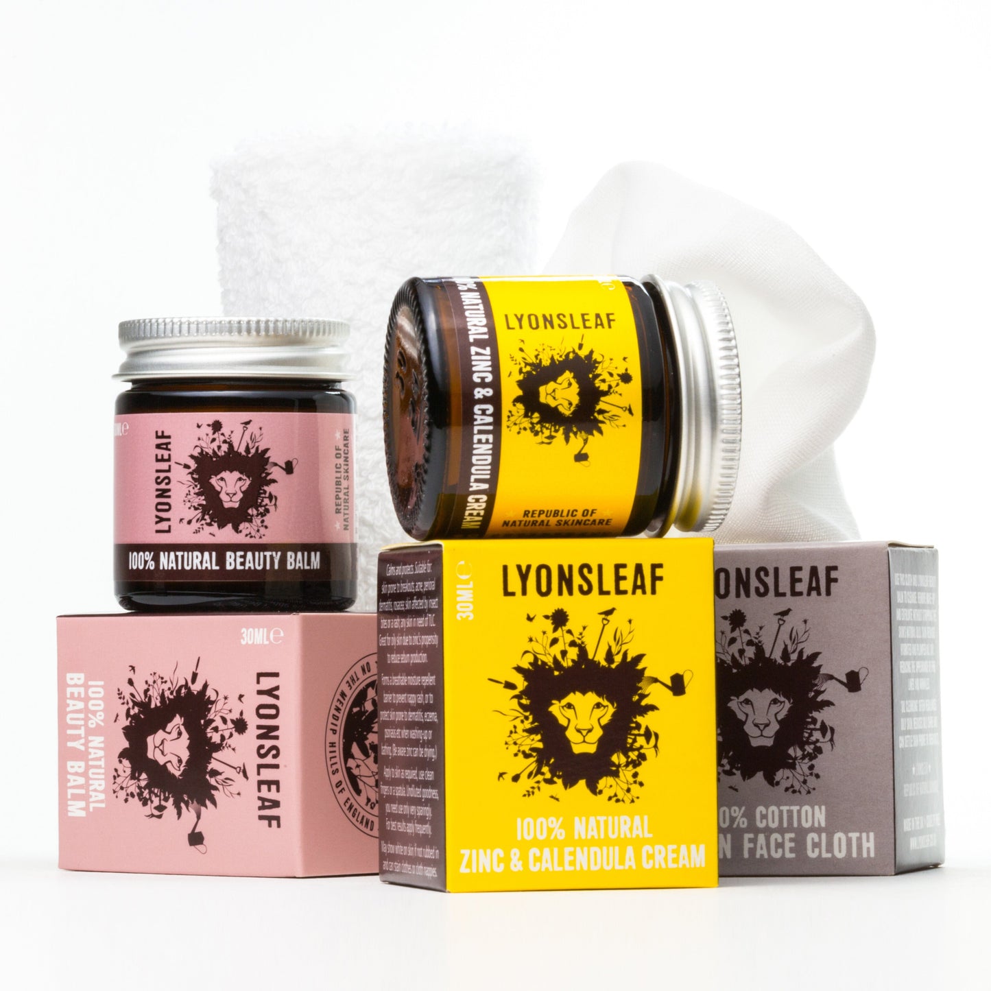 A neatly arranged display of Lyonsleaf skincare products, including jars of 100% Natural Beauty Balm and Zinc & Calendula Cream, alongside a 100% cotton face cloth. The products are in distinctive packaging with the brand's logo and lion graphic prominently featured.