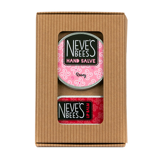 photo of natural handmade skincare products on a white background. the product in the photo is a duo of balms handmade from beeswax, plant butters and essential oils. The products are in a brown striped rectangular box with a window. Inside the window you can see the two products in aluminium tins with red and pink labels. There is a rosey hand slave and a rosey lip balm