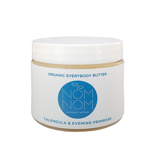 Nom Nom Organic everybody butter on a white background. the product comes in a clear glass jar with white plastic lid and white label with blue accents with Nom Nom name and logo.