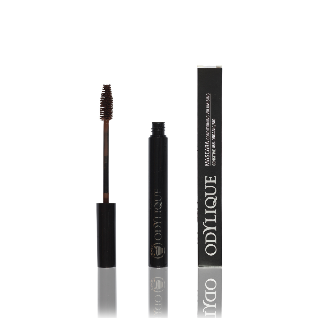 Mascara tube with the brush applicator removed and placed next to its corresponding black and silver packaging with "odylique" brand logo visible.