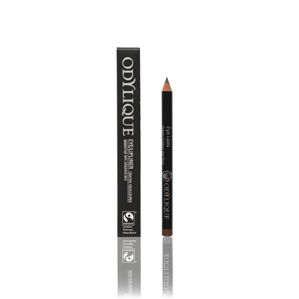 A photo of a dark brown Eye/Lip pencil next to its packaging, both labeled ‘Odylique’ with a shiny, reflective white surface background.