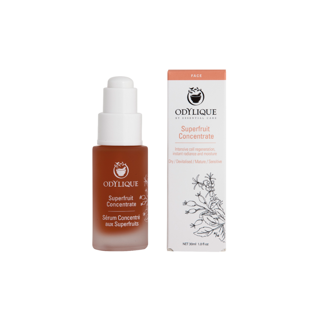 Odylique Superfruit Concentrate Organic Serum. Certified organic skincare. A bright orange serum in 30ml glass bottle with white pump, shown next to the white and pink paper box package. It is illustrated with botanics and black and pink text.