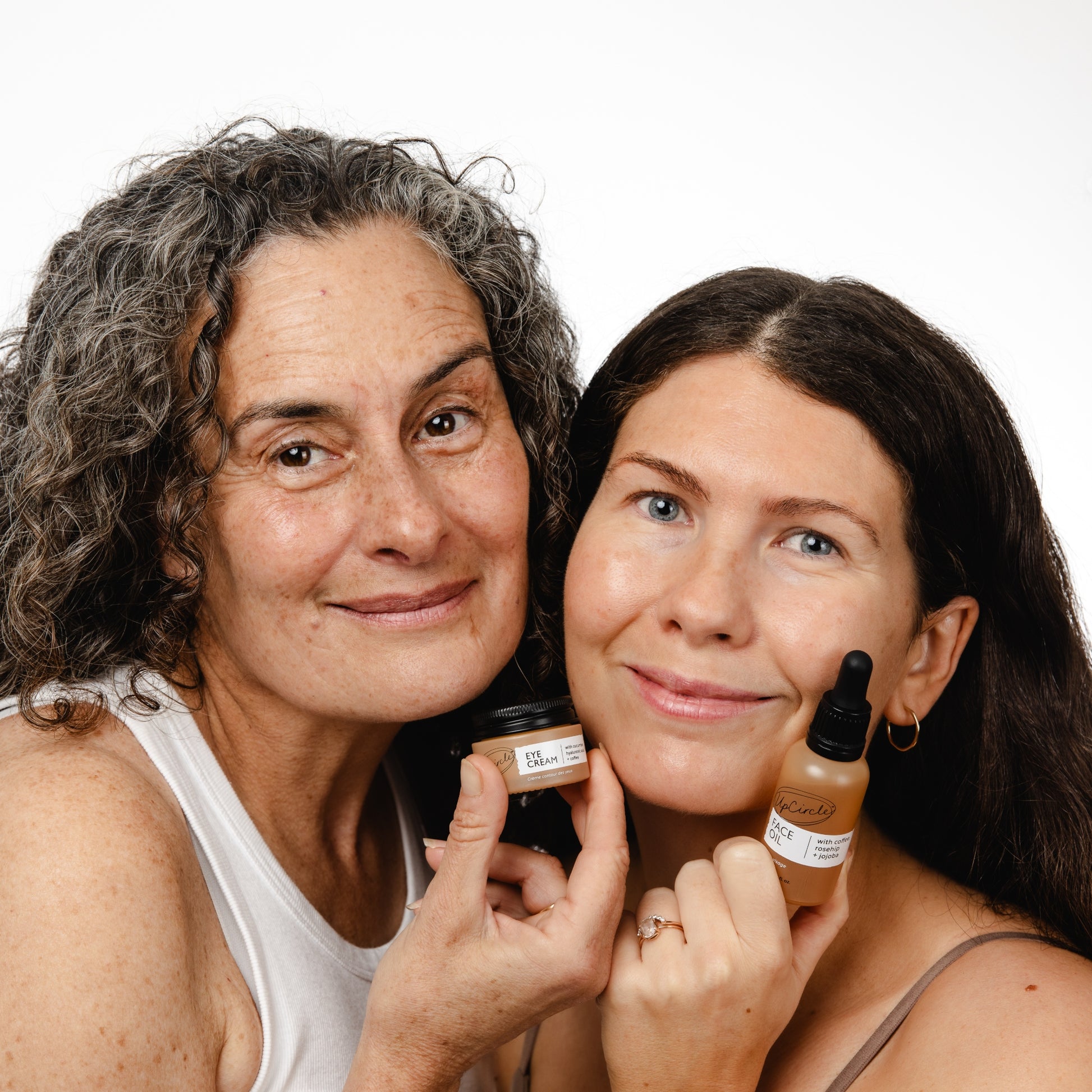 2 women holding up the upcircle eye cream and face oil together