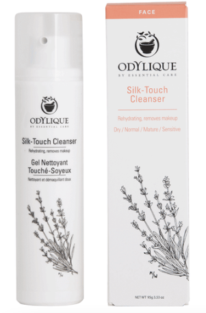 Odylique silk touch cleanser shown outside of the cardboard box which has a peach accent on the shop. The white box and white recyclable plastic bottle has a line drawing of lavender and the text reads 'silk touch cleanser. rehydrating, removes make up'