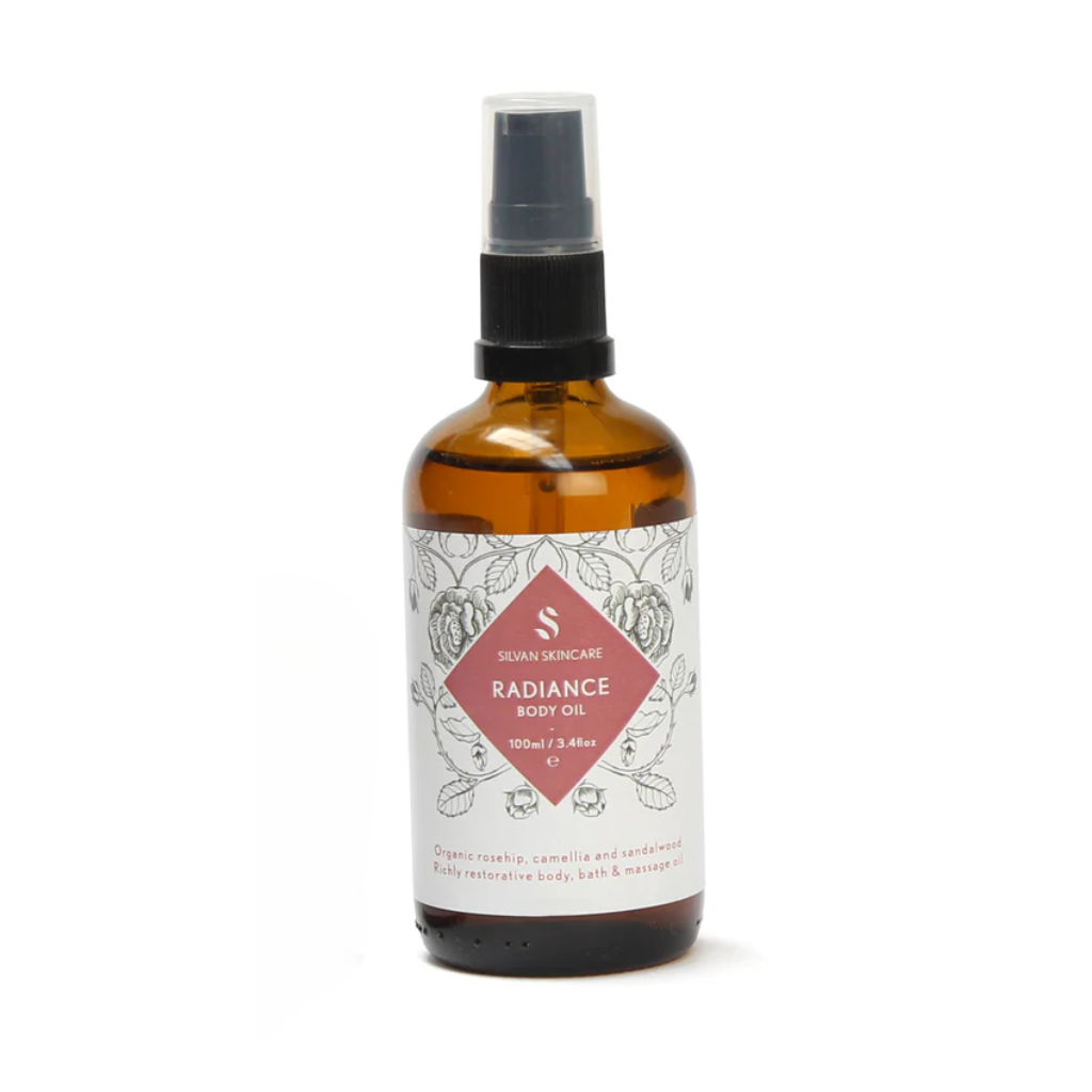 Silvan Skincare Radiance Body Oil in an amber glass bottle with a white label and a pink diamond in the middle. The bottle is against a white backdrop. Natural Body Oil