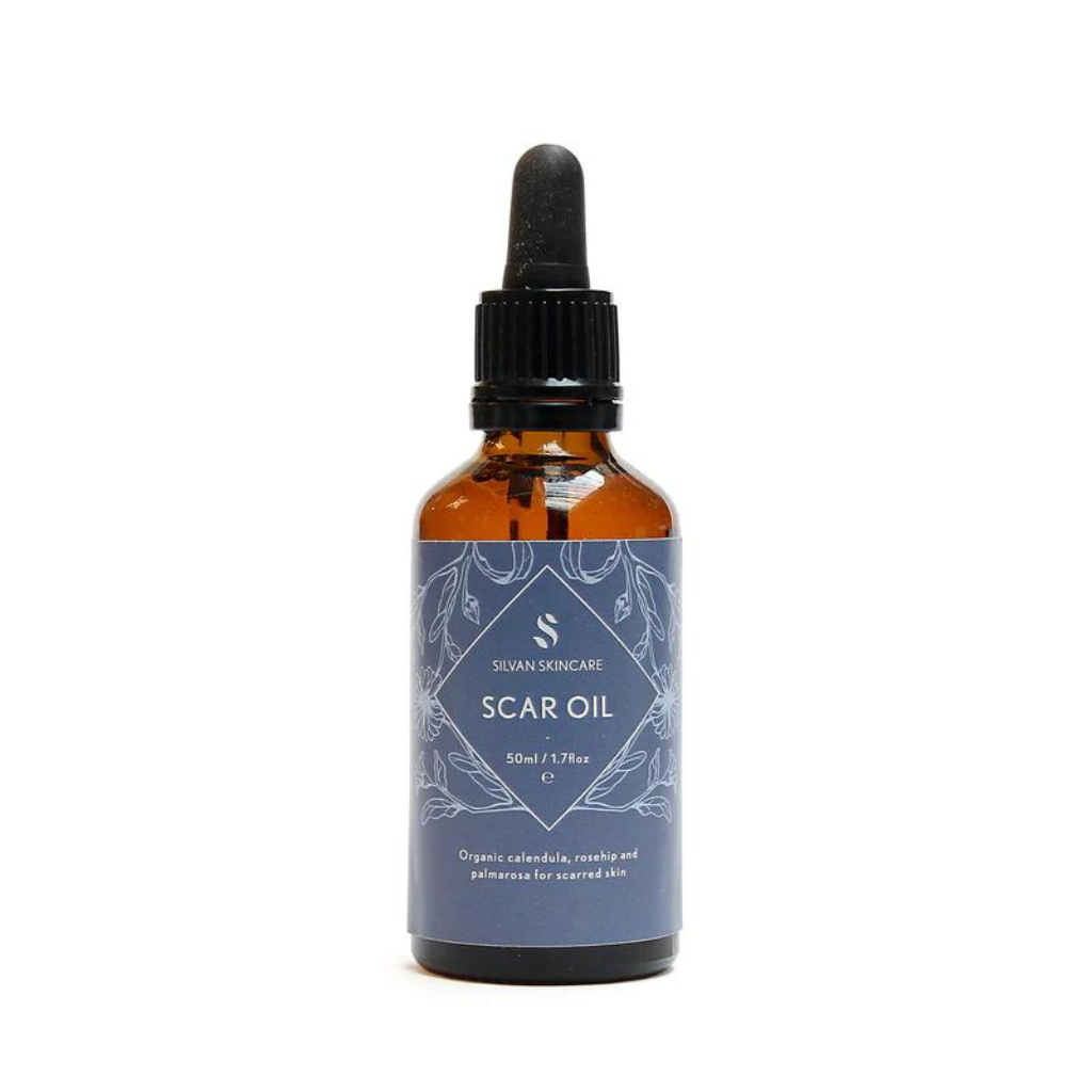 vegan and cruelty free oil for scarring photographed on a white background. the oil comes in an amber glass bottle with black plastic pipette lid and a grey blue label
