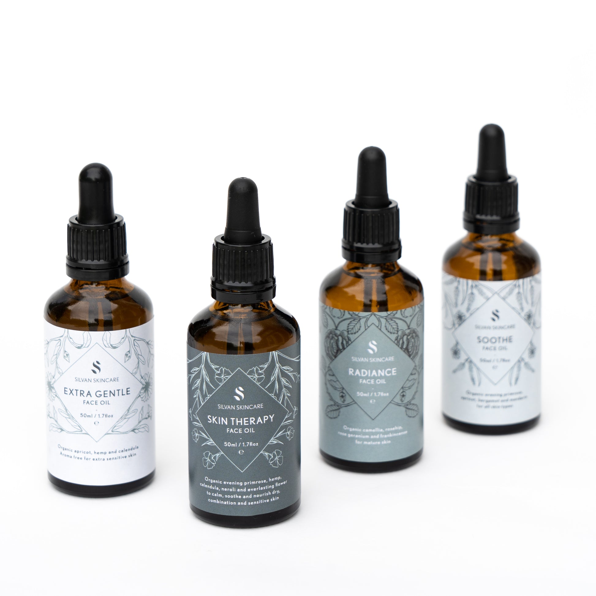 set of 4 face oils in amber bottles with different gradient blue/grey labels