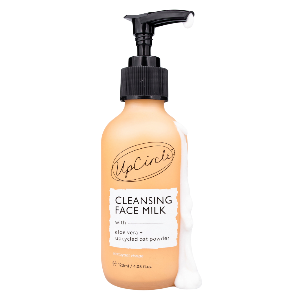upcircle beauty's cleansing face milk with aloe vera and upcycled oat powder in an orange glass bottle with black plastic pump and white creamy cleanser running down the side on a white background