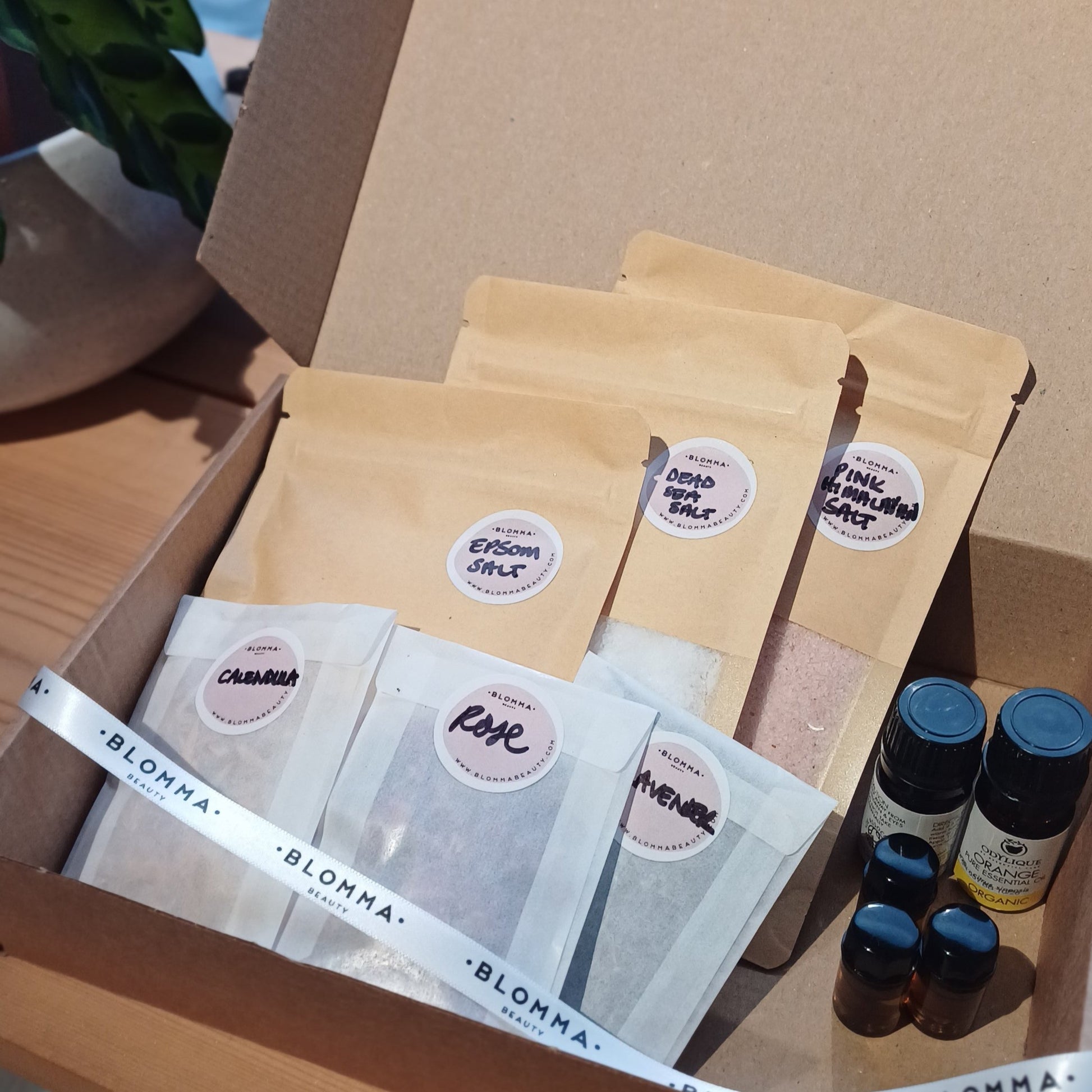 brown box containing ingredients to make your own bath salts. salts, dried flower petals and base and essential oils in paper sachets and small glass bottles