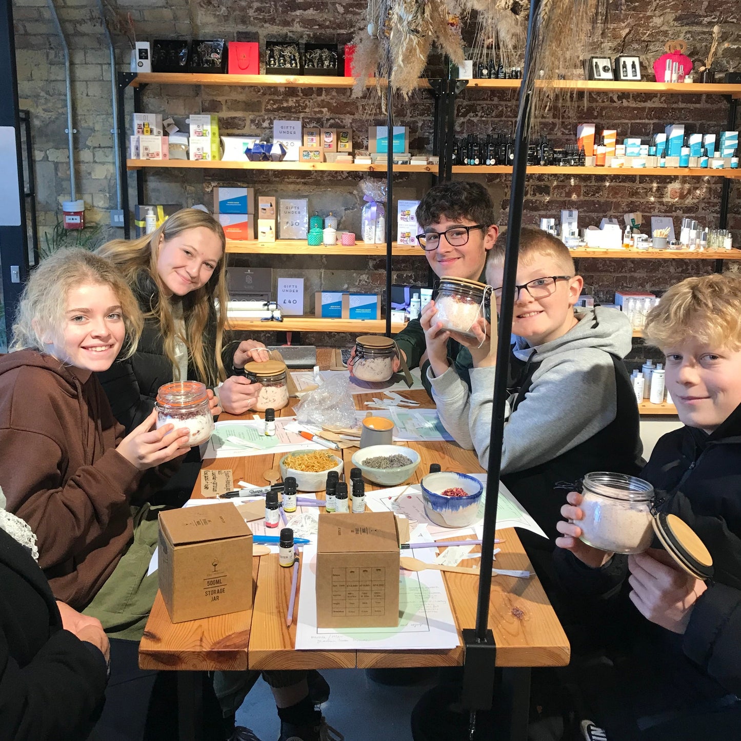 group of teenage boys and girls showing off their bath salts they have made at a blomma beauty natural skincare workshop