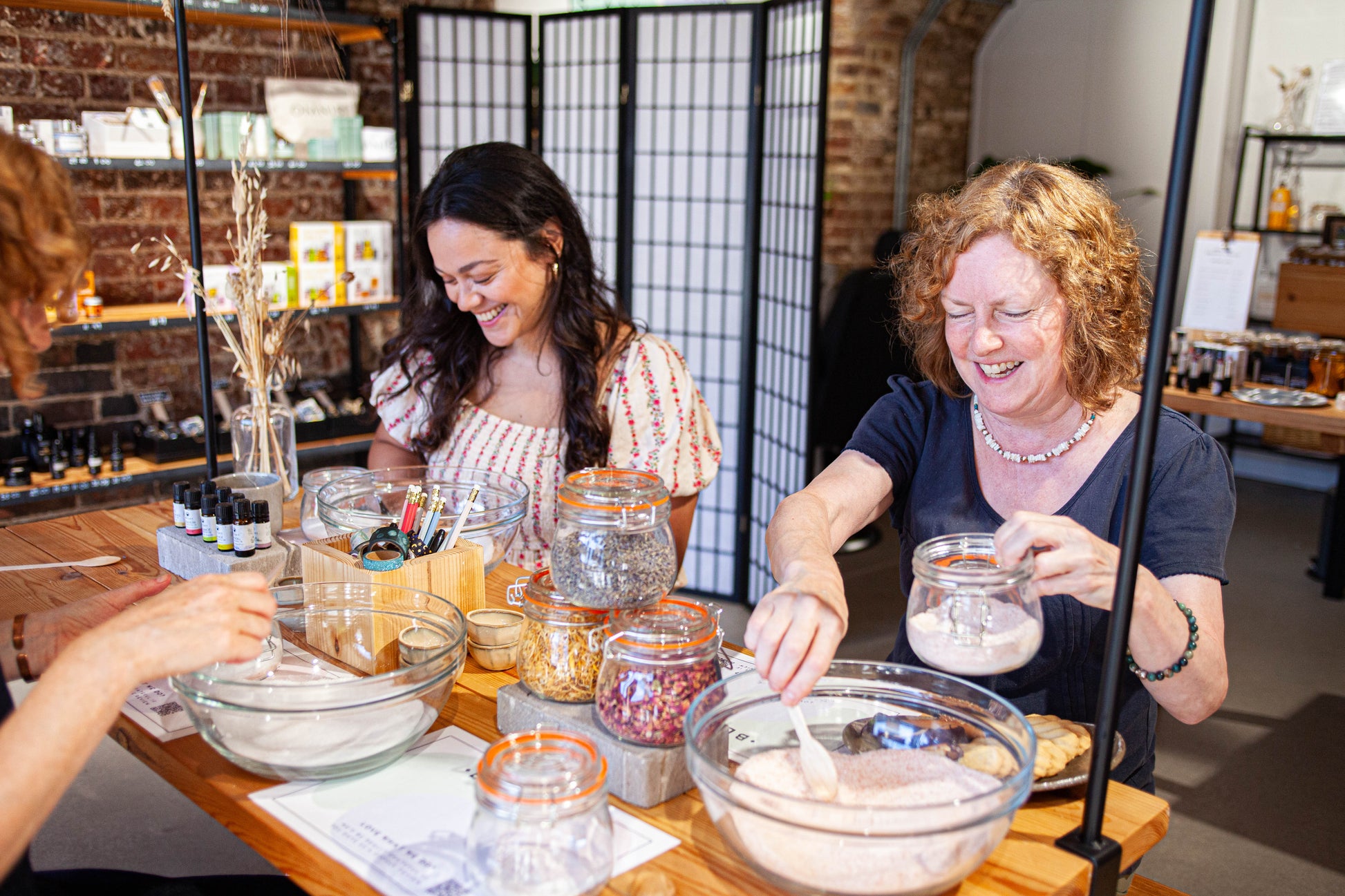 2 women blending salts and flowers to make  handmade body scrub