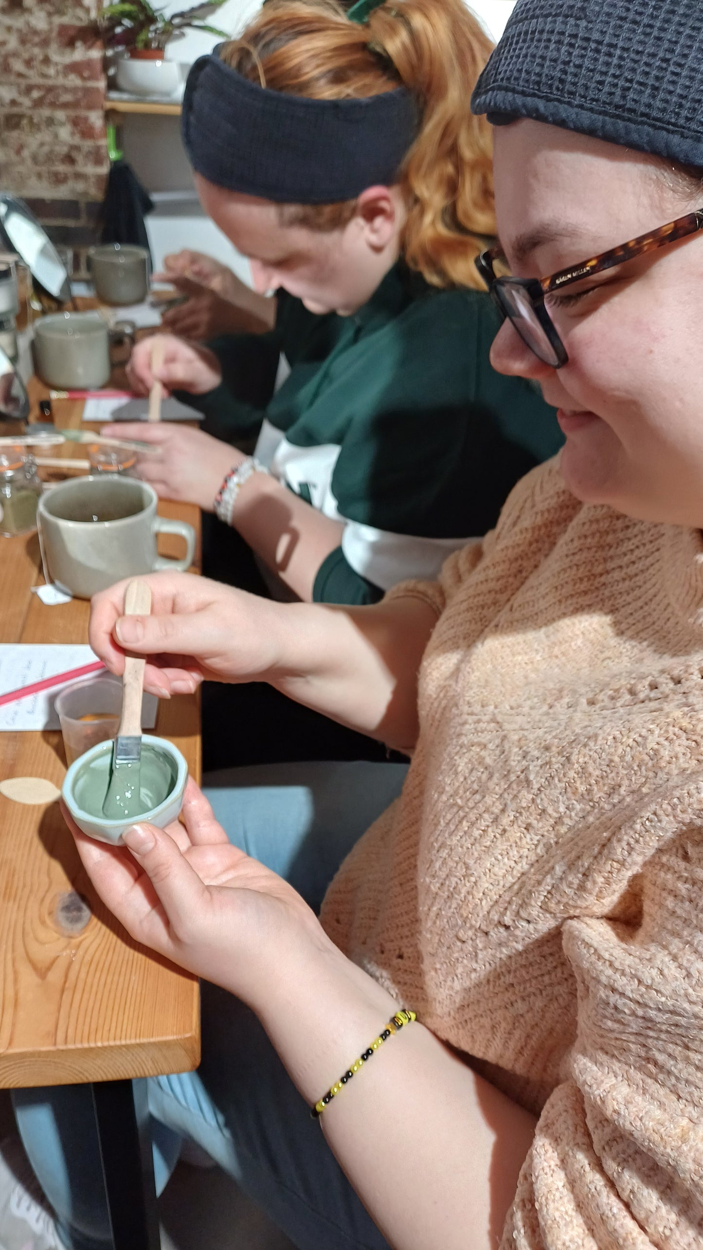 showing 2 women wearing cosmetic headbands mixing up their bespoke clay face mask recipes before applying them on their fcaces