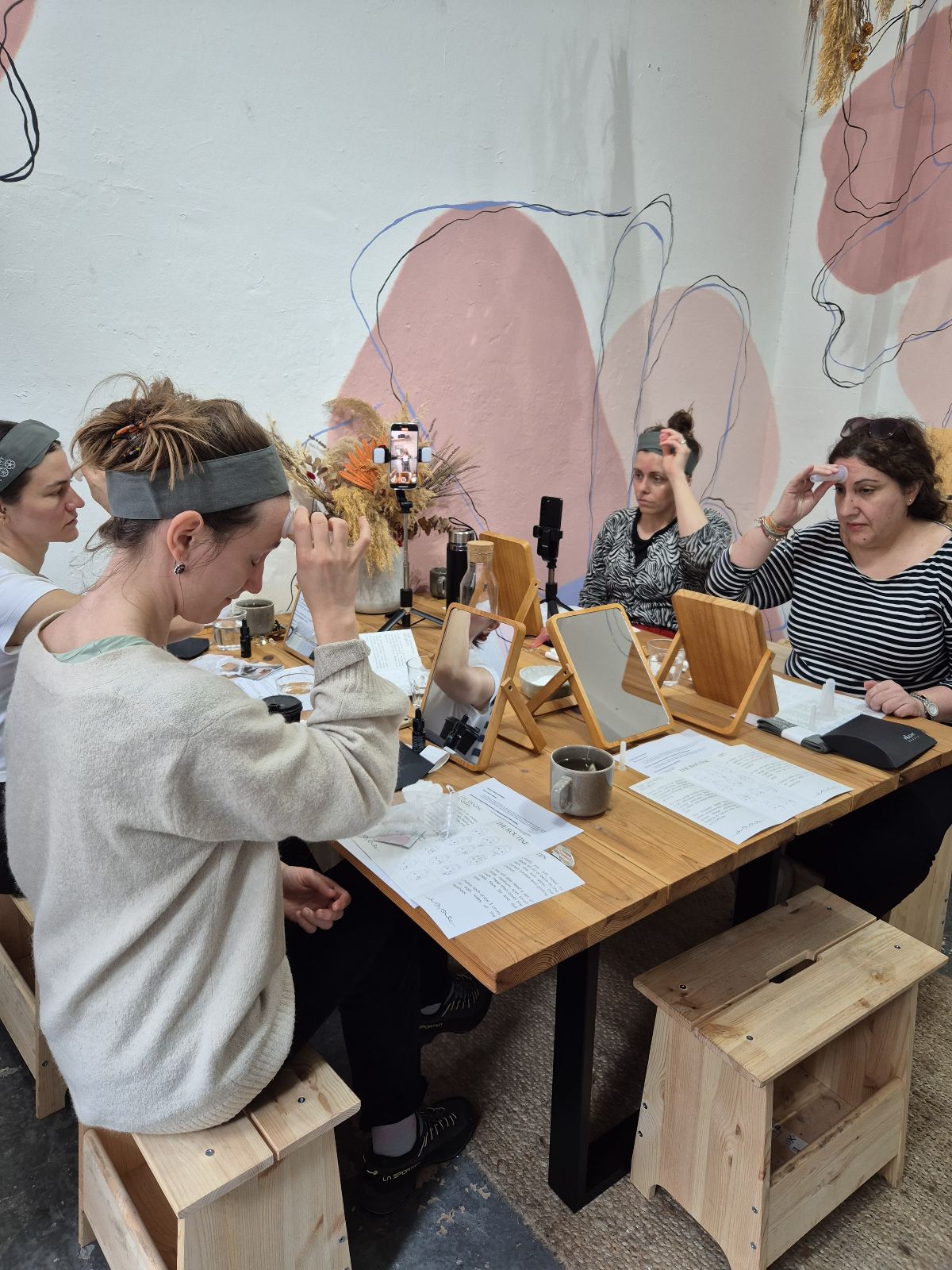 group of women around a table using facial cups in a guided class