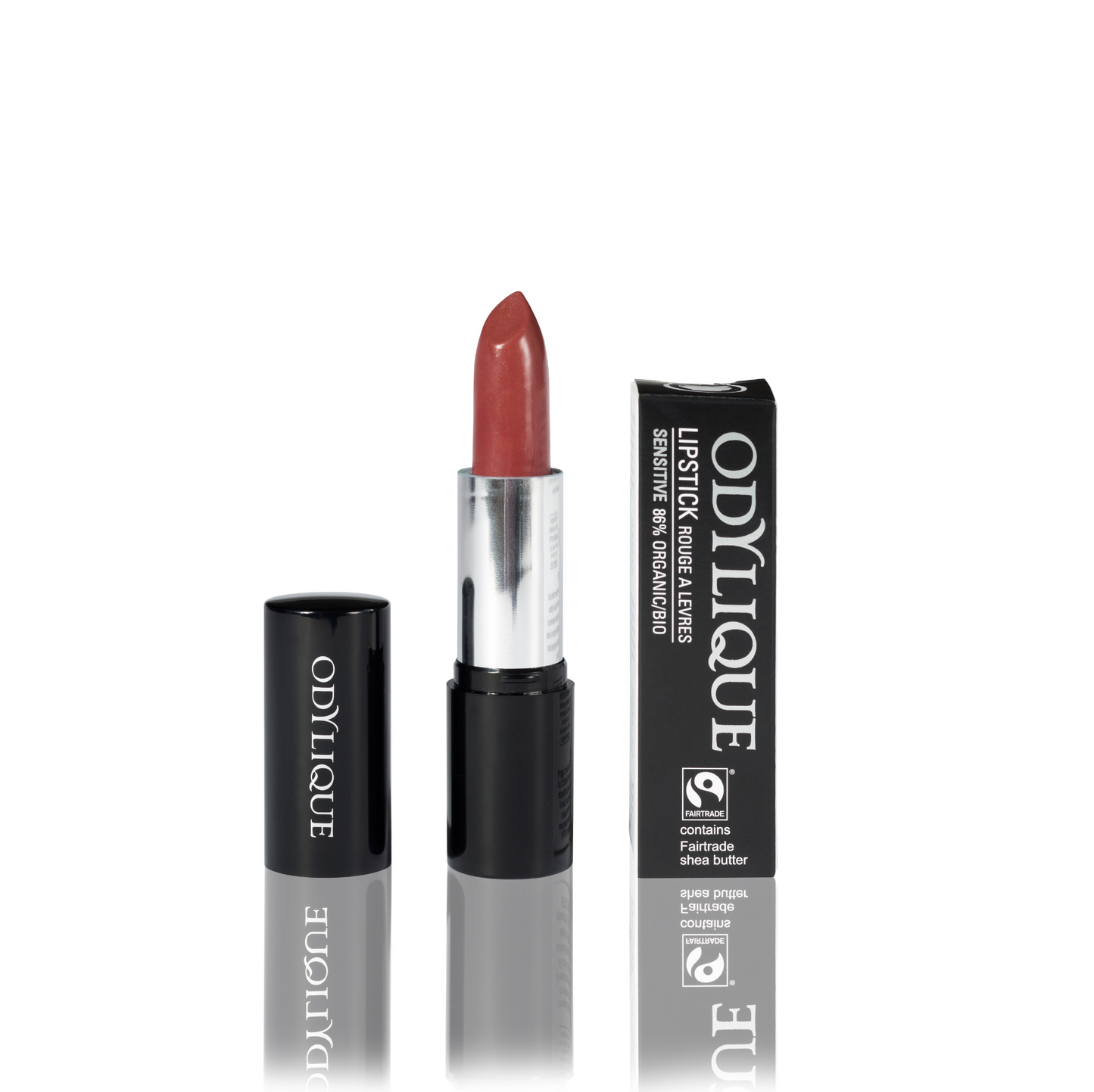 Odylique lipstick in Fig Fondant (warm burnished pink) partially twisted up from its black tube, positioned next to its packaging on a reflective surface.