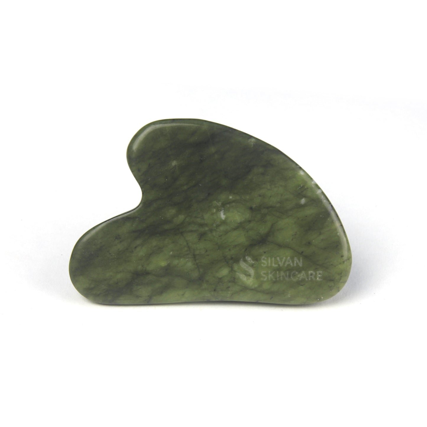 a heart shaped facial massage stone made from natural green jade. on the bottom right corner you can see the silvan skincare logo has been etched into the stone