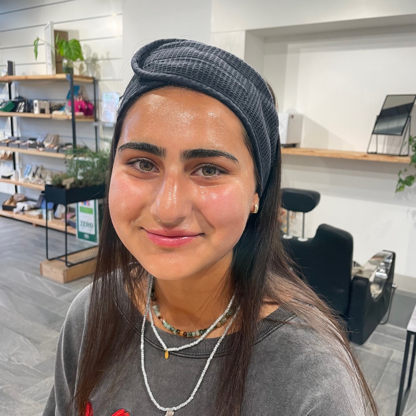 woman with long dark hair wearing a black beauty hair band with glowing skin during a guided self-care skincare experience in london