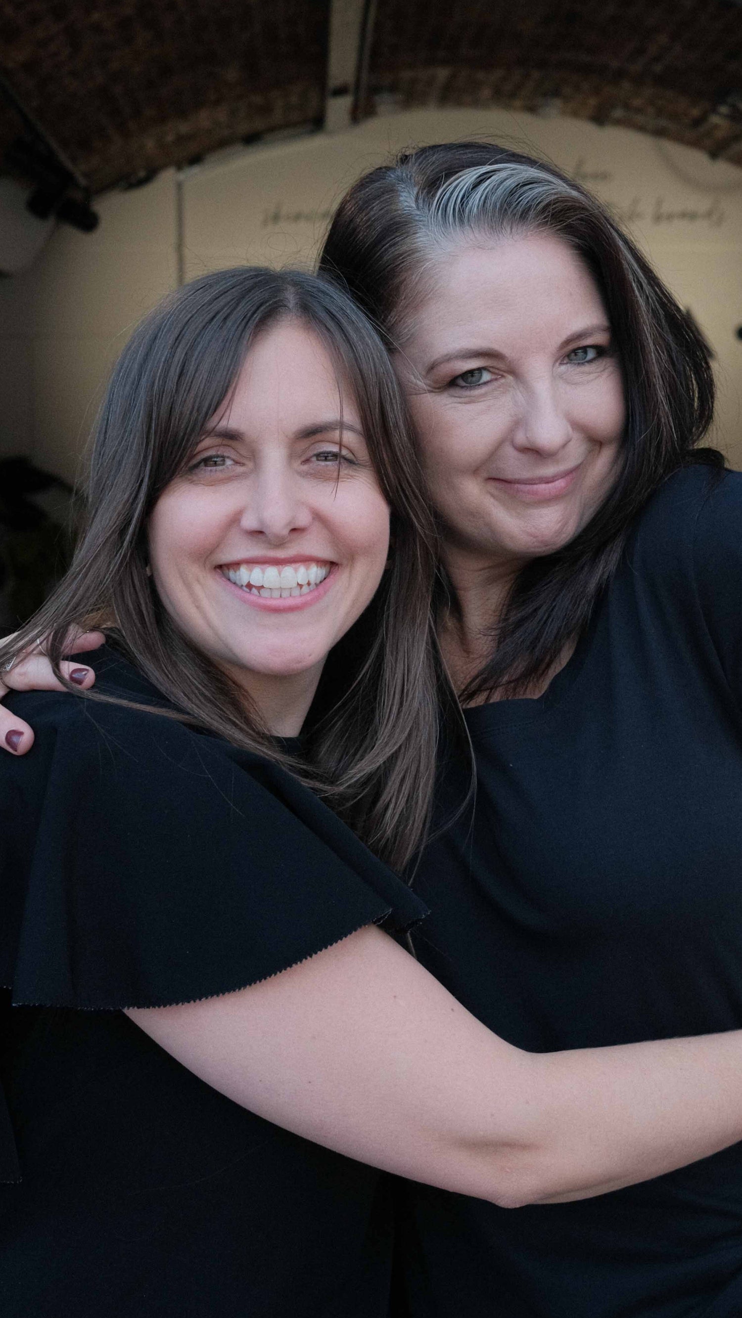2 women wearing black hugging outside natural skincare shop in london