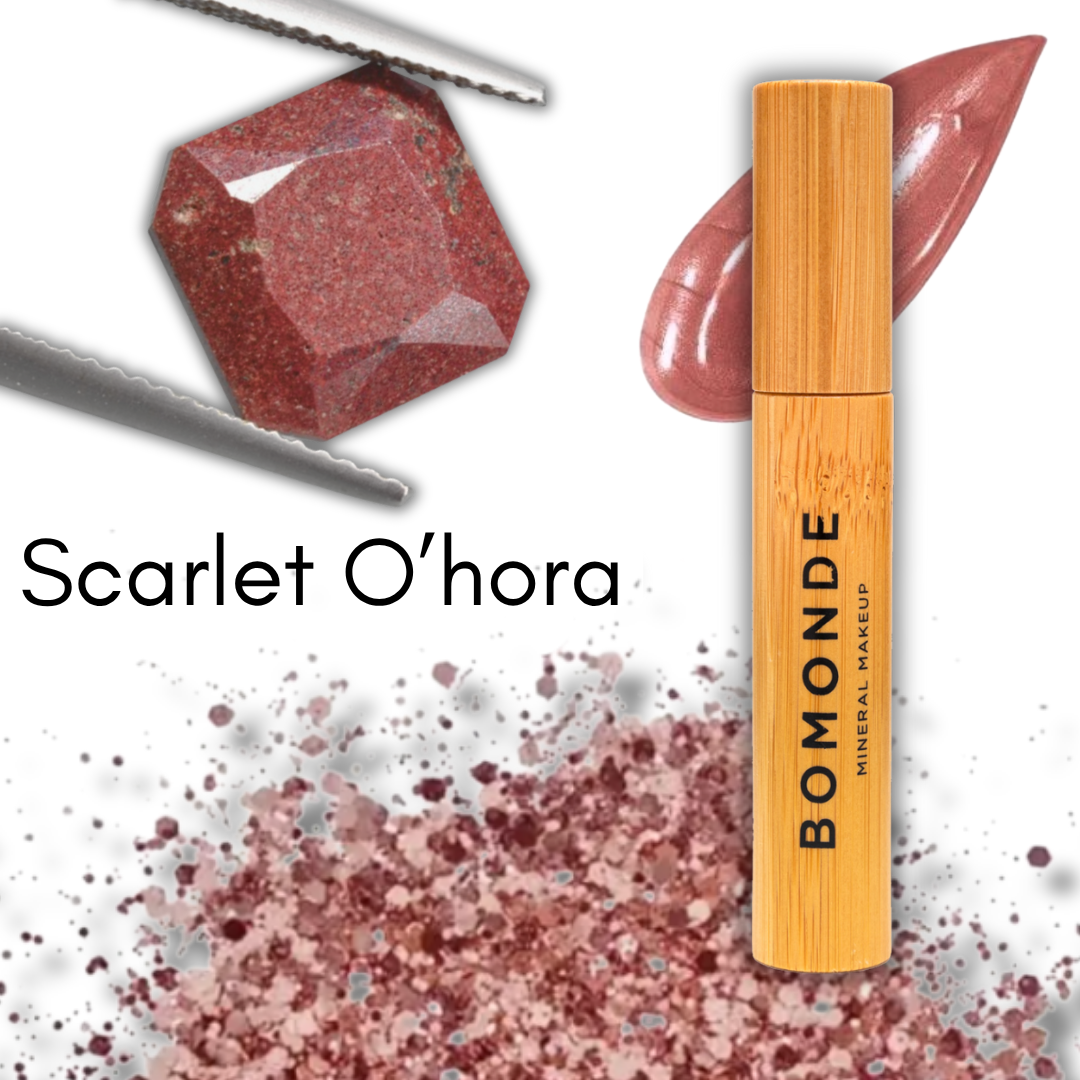 illustration to show the colour of the scarlet ohara lip gloss/liquid lipstick shade from vegan make up brand bomonde. there is a caramel coloured gemstone held in tweezers and some multicolourer neutral gemstone fragments next to a tube of the lip colour and swatch of what the gloss looks like
