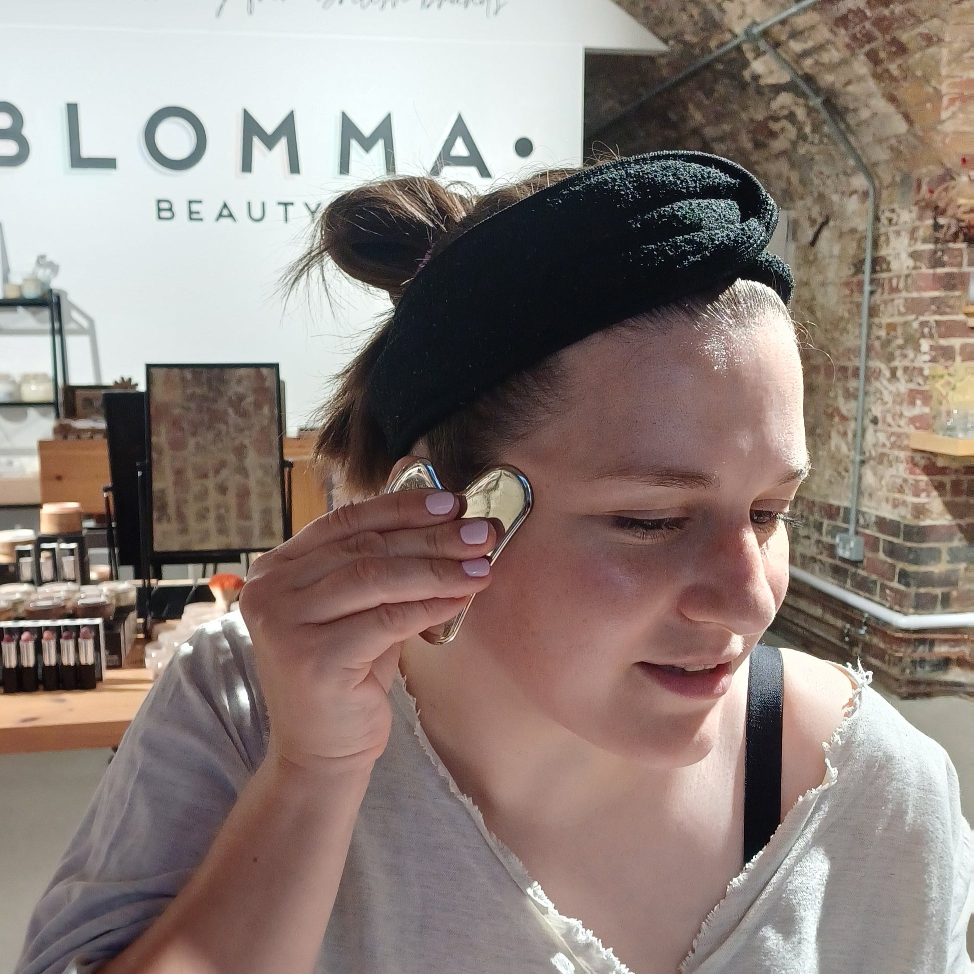 learner at the gua sha class at blomma beauty using a stainless steel gua sha tool along the eye and temple