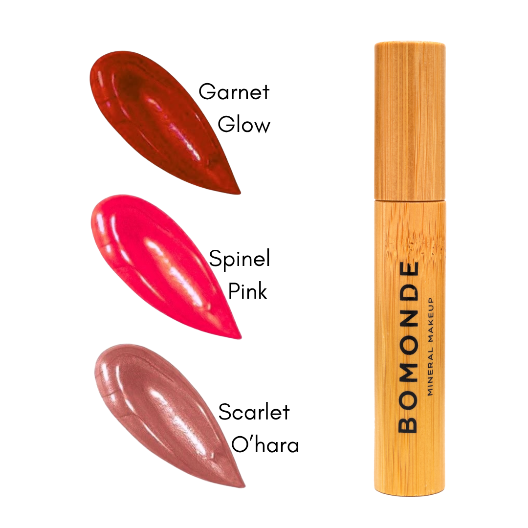 3 different tones of liquid lipstick from bomonde shown next to the bamboo tube and applicator stick. garnet glow - a deep red, spinel, a bright shimmery pink, scarlet ohara, a peachy neutral