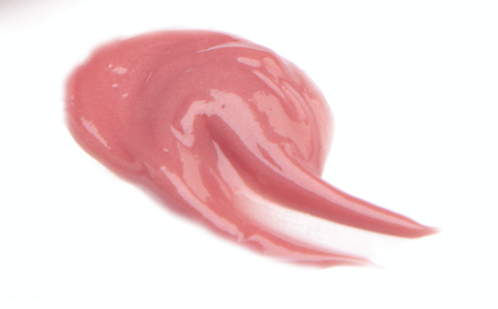 BareFaced Beauty Natural Mineral Lip Gloss in Blissful. Natural lip gloss. A dollop of gloss is spread on a white surface. The shade is a salmon pink.