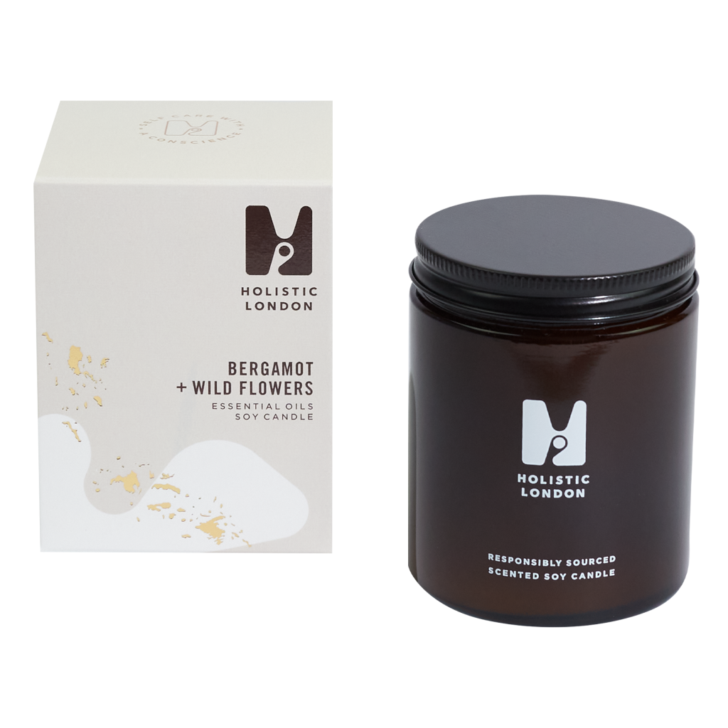 photograph of holistic london's bergamot + wildflowers 180g soy based candle on a white background. on the left side of the image is the light beige cardboard box with the holistic london logo on it. the label reads 'bergamot + wildflowers essential oils soy candle'. on the right side of the photo is the amber jar with a black aluminium lid which holds the candle. the glass is printed with the holistic london logo and says 'responsibly sourced scented soy candle'
