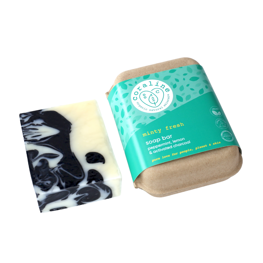 A bar of the minty fresh soap - a white soap bar with dark blue marbling placed next to its eco-friendly packaging. The packaging is brown recycled carton with a green label that reads "minty fresh," with “peppermint, lemon & activated charcoal,"