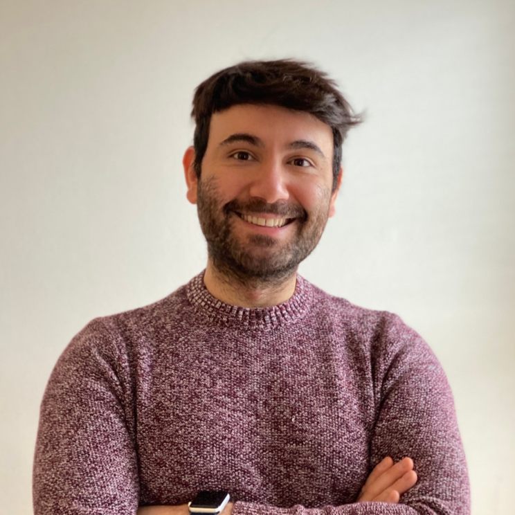 Haoma Founder Enis. Enis is pictured smiling with his arms crossed in a burgundy and white cable knit sweater.