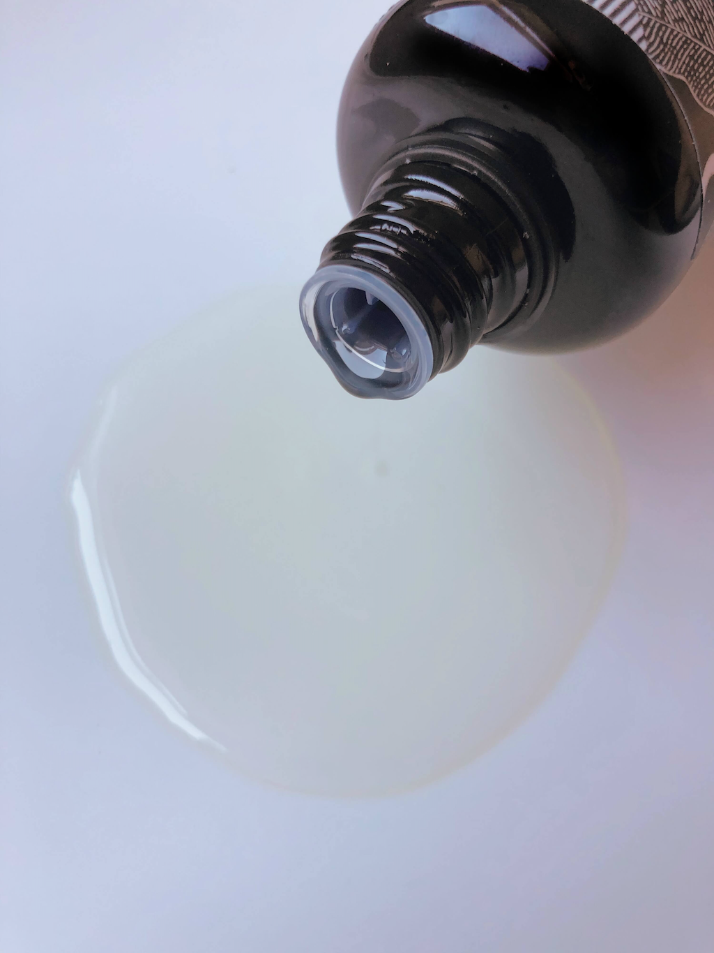 Haoma Organic Massage Oils. Natural body oils. A black glass bottle of oil is pictured in the top corner of the frame with a puddle of oil spilling out of the top.