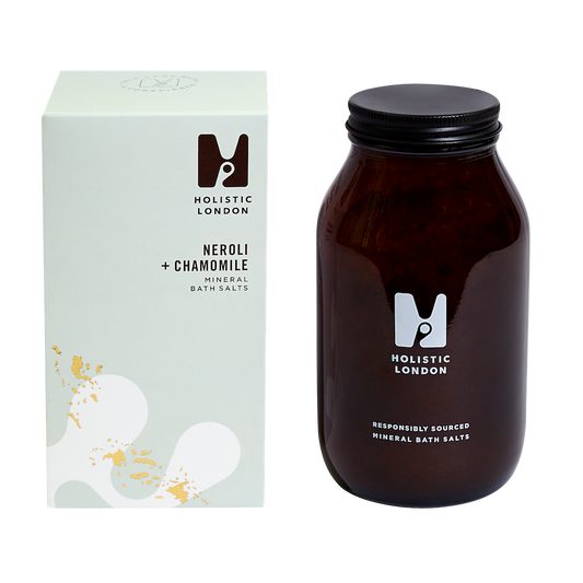 Holistic Neroli and Chamomile Mineral Bath Salts. Cruelty free bath salts. The salts are pictured in an amber glass jar with a black aluminium ild next to a green box.