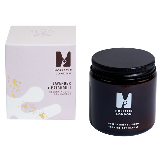photograph of holistic london's lavender and patchouli 120g soy based candle on a white background. on the left side of the image is the light purple cardboard box with the holistic london logo on it. the label reads ' lavender and patchouli essential oils soy candle'. on the right side of the photo is the amber jar with a black aluminium lid which holds the candle. the glass is printed with the holistic london logo and says 'responsibly sourced scented soy candle'