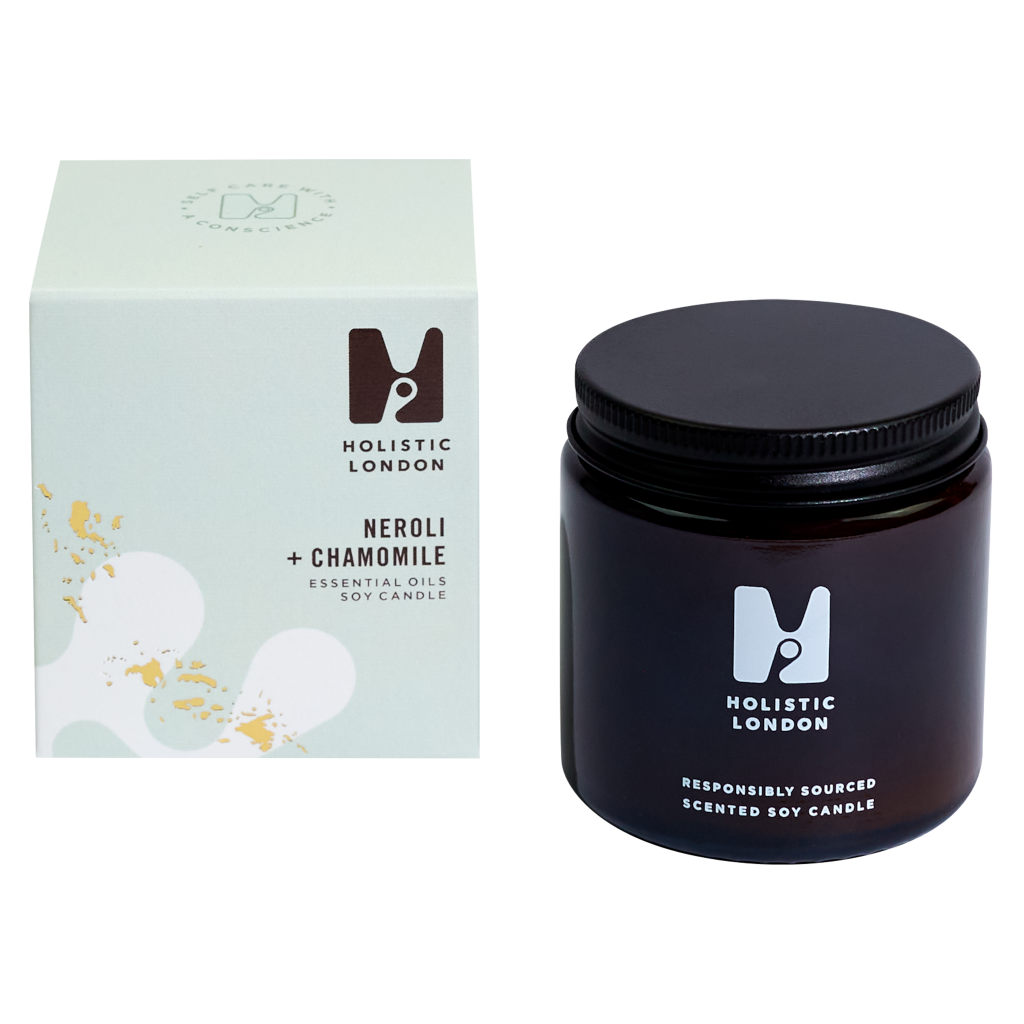 photograph of holistic london's neroli + chamomile 120g soy based candle on a white background. on the left side of the image is the light green cardboard box with the holistic london logo on it. the label reads 'neroli + chamomile essential oils soy candle'. on the right side of the photo is the amber jar with a black aluminium lid which holds the candle. the glass is printed with the holistic london logo and says 'responsibly sourced scented soy candle'