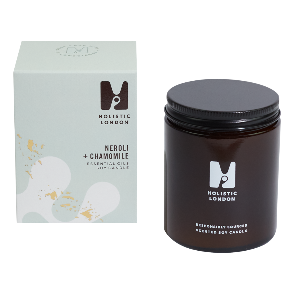 photograph of holistic london's neroli + chamomile 180g soy based candle on a white background. on the left side of the image is the light green cardboard box with the holistic london logo on it. the label reads 'neroli + chamomile essential oils soy candle'. on the right side of the photo is the amber jar with a black aluminium lid which holds the candle. the glass is printed with the holistic london logo and says 'responsibly sourced scented soy candle'