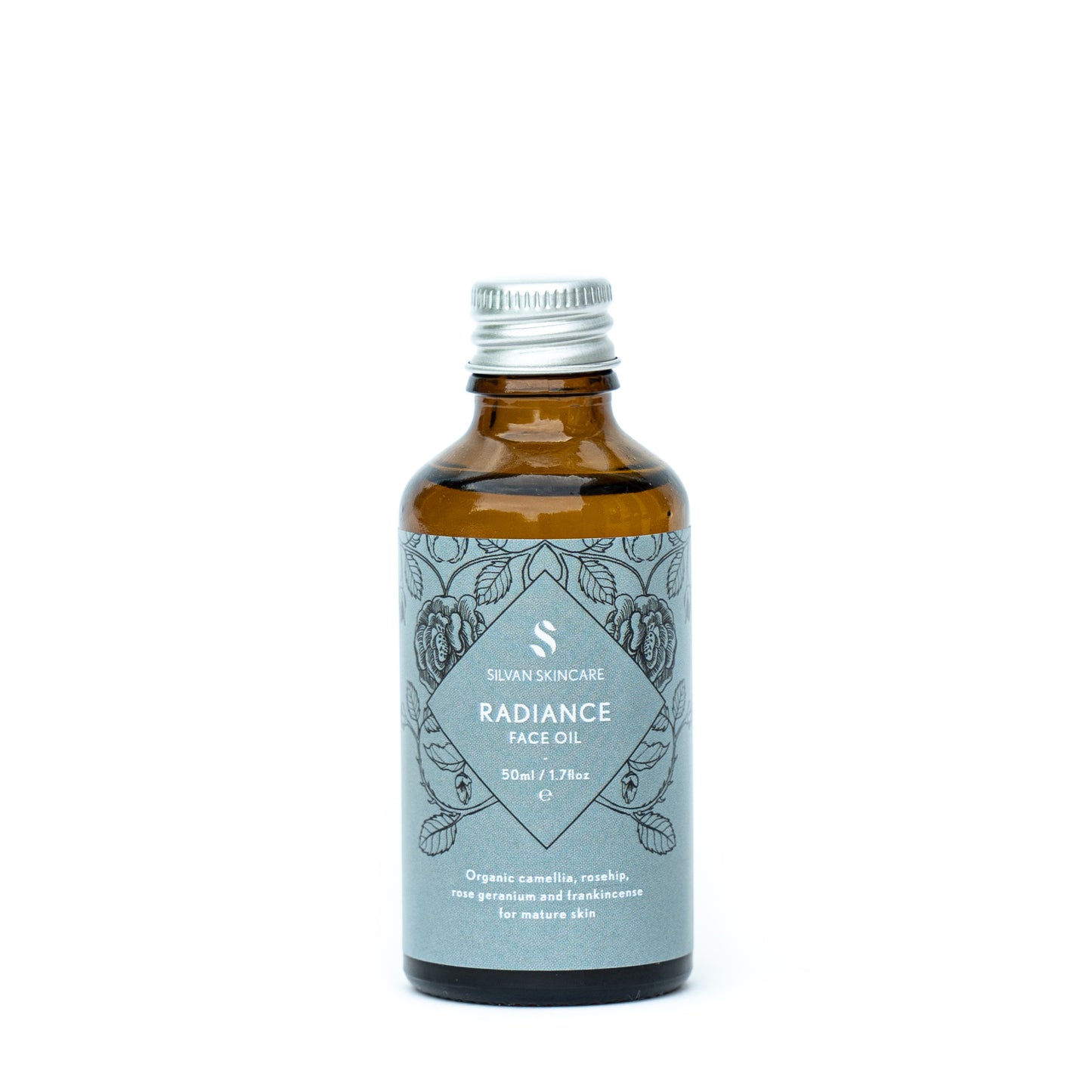 Silvan Skincare Radiance Face Oil refill bottle. The facial oil is inside an amber glass bottle with a silver aluminium screw top. The bottle has a blue label, white text listing the product and brand and black botanical illustrations.