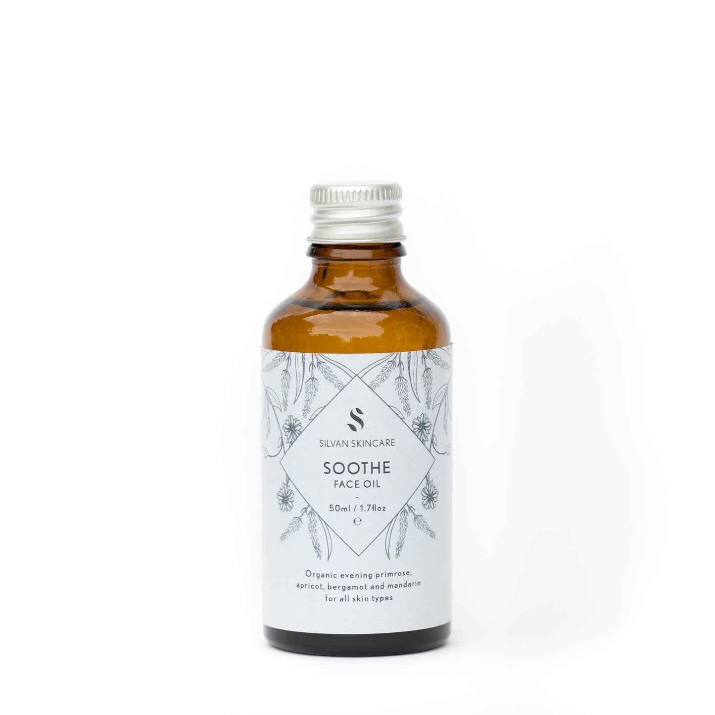 Silvan Skincare Soothe face oil refill bottle. The facial oil is inside an amber glass bottle with a silver aluminium screw top. The bottle has a light blue label, black text listing the product and brand and black botanical illustrations.