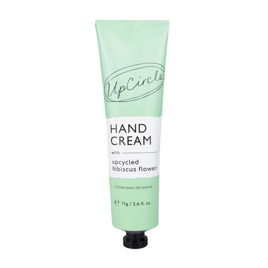 image of upcircle beauty's hand cream on a white background. the handcream comes in a sea green aluminium tube with a black plastic cap. the label reads 'upcircle hand cream with upcycled hibiscus flowers creme pour le mains 75g'