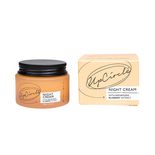 An orange glass jar of UpCircle night cream sits on a white background. It has a black aluminium lid and is placed next to the plastic free packaging box it comes in, on the right.