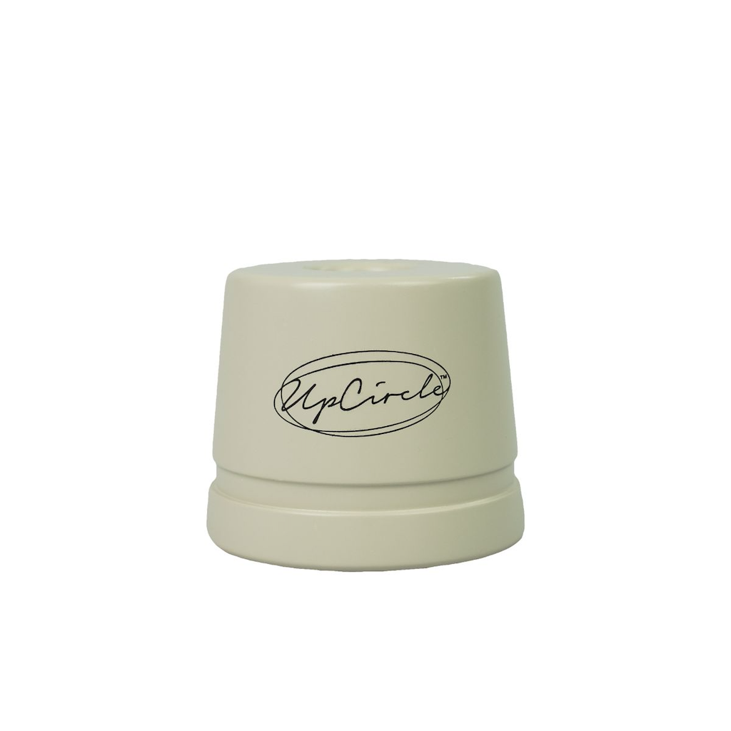 A circular, cream-coloured razor stand is stood against a white background