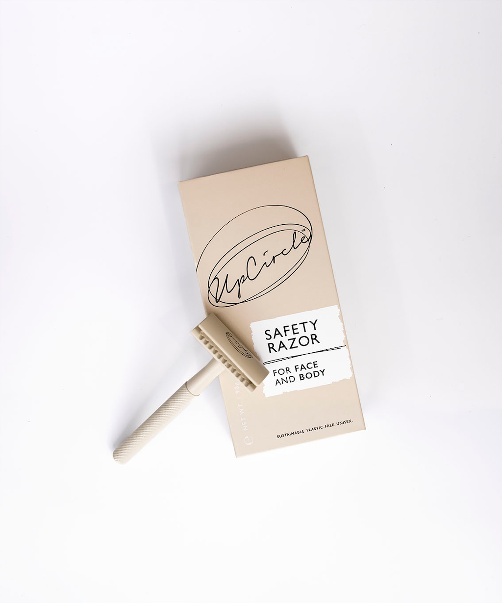 Upcircle safety razor box laid flat on a white background and the razor itself is propped up against the box