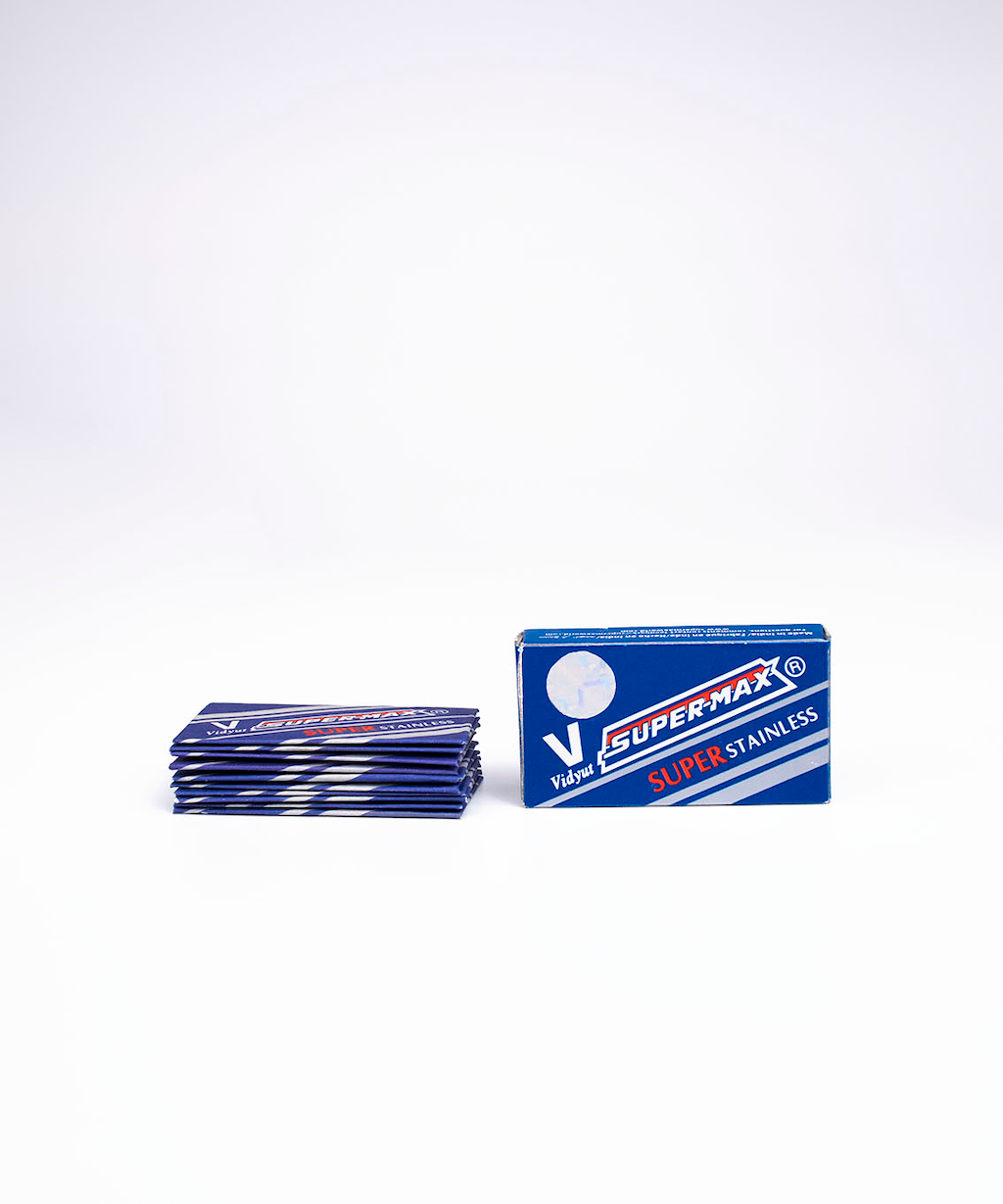 Blue Super-Max Super Stainless razor blade packaging. The blades stacked up next to it, on the left.
