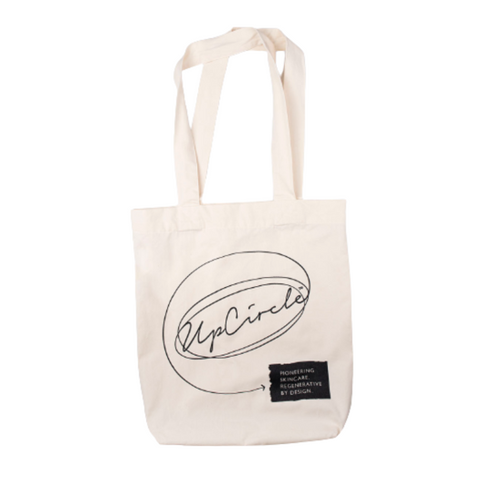 An image of the upcircle tote bag made from cotton and beige coloured. The brand name is printed in black.