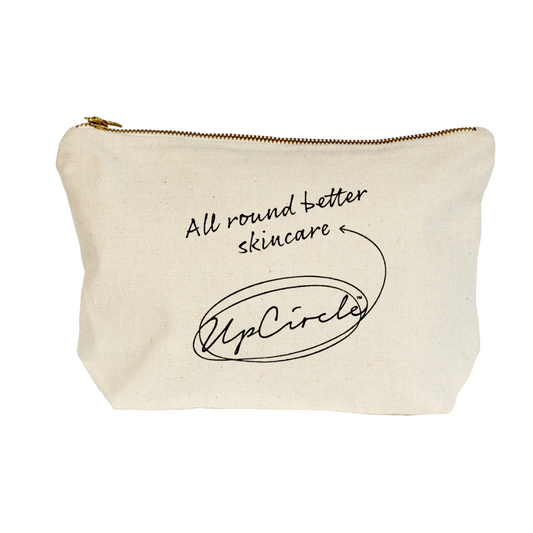 The upcircle wash bag against a white background. The wash bag is made from 100% Fairtrade heavyweight cotton and is beige in colour. It has a gold coloured metal zipper and printed black text that reads "all round better skincare" and "UpCircle".