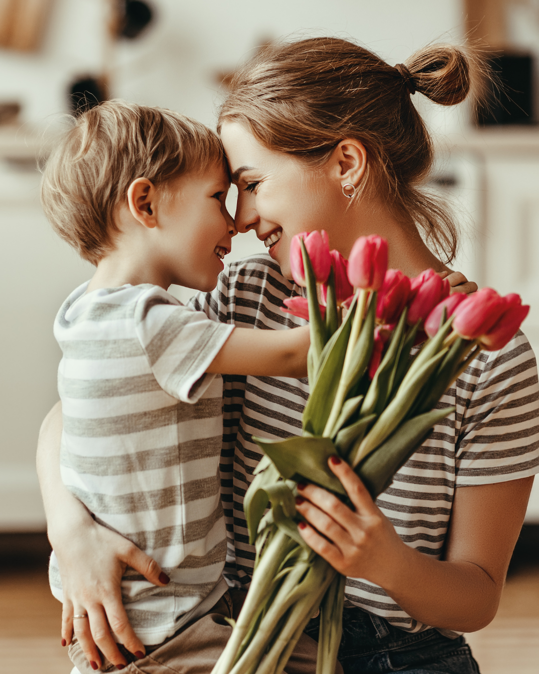 photo of a little boy and a mum both with stripey brown and cream t shirts hugging and holding some tulips