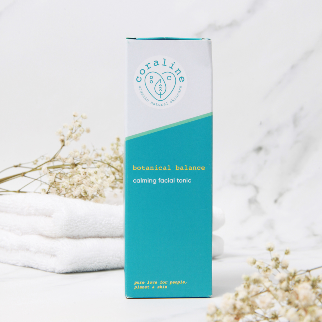 boxed up bottle of coraline skincare botanical face mist in a white marble background with two stacked white towels with creamy dried gypsophelia on the towels and in the foreground