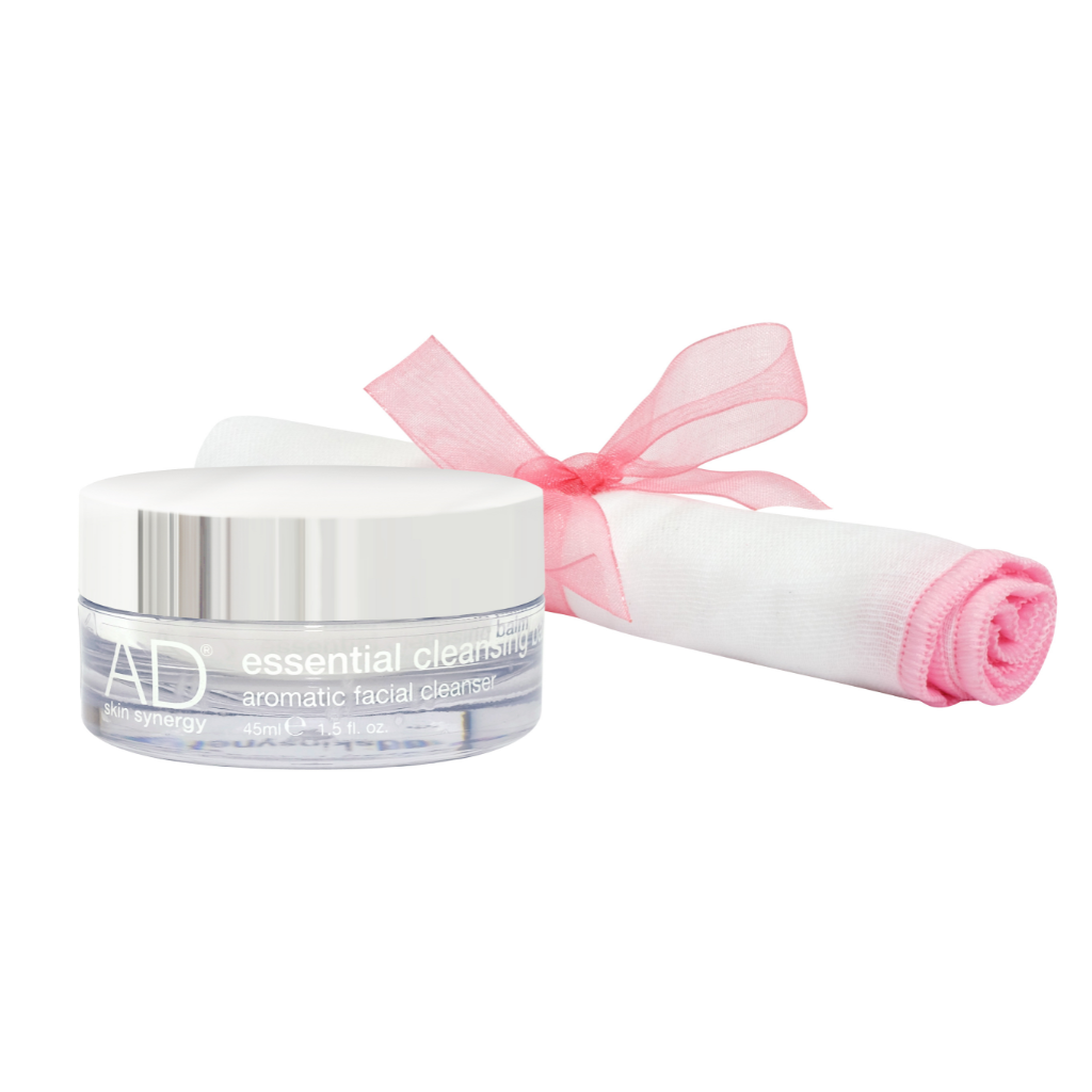 AD skin synergy cleansing balm in a clear acrylic pot and silver lid, with the Organic white Muslin Face Cloth, which is lined with pink stitching and rolled up with a pink lace bow.