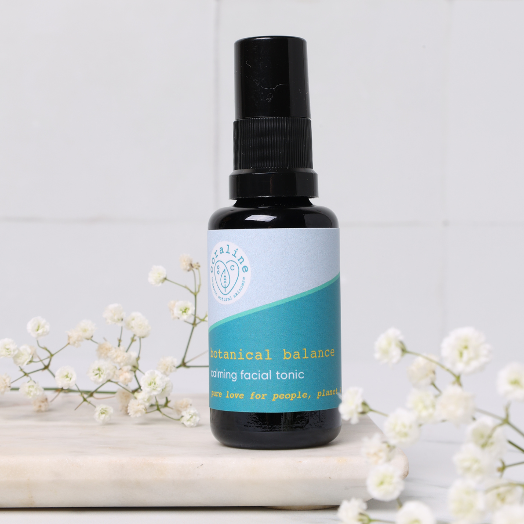 small size 30ml facial toning spray for travel size. in a black spray bottle on top of a white tile and with small white flowers surrounding it