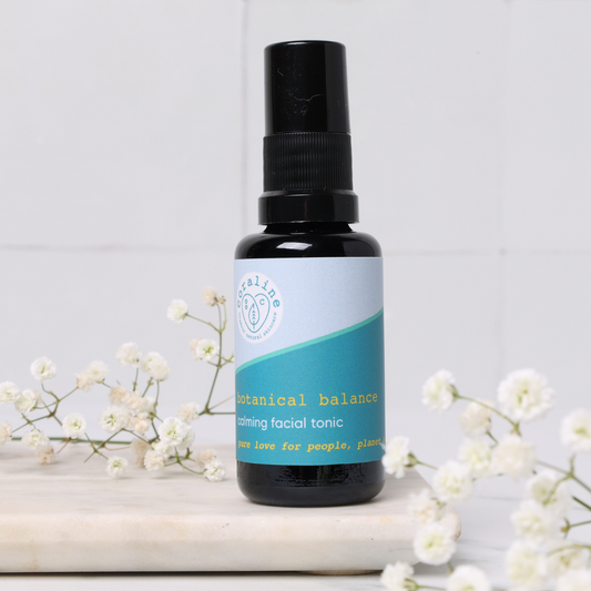 small size 30ml facial toning spray for travel size. in a black spray bottle on top of a white tile and with small white flowers surrounding it